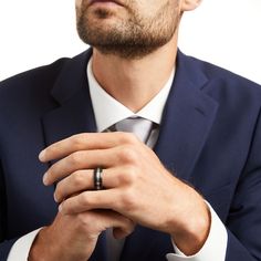 a man wearing a suit and tie with his hands folded