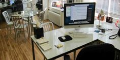 a desk with a computer monitor, keyboard and mouse on it in a room full of chairs