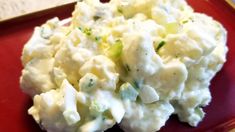 a red plate topped with potato salad on top of a table