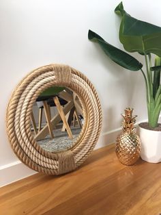 a mirror sitting on top of a wooden table next to a potted plant and pineapple