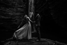 a man and woman standing in front of a waterfall