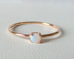 EACH PICTURE WAS TAKEN UNDER DIFFERENT LIGHT SO YOU CAN REALLY APPRECIATE THE WIDE SPECTRUM OF COLORS OF THE OPAL.  HANDMADE DELICATE AND DAINTY WHITE AUSTRALIAN ROUND OPAL IS SET IN A BEZEL 14K ROSE  GOLD RING. ONE OF MY VERY FAVORITE STONES BECAUSE OPALS HAVE THEIR OWN PERSONALITY, COLOR, AND DNA. NO TWO OPALS ARE THE SAME. THIS ONE IS FULL OF BLUES AND GREENS AND LIGHT PURPLE HUES. NATURAL WHITE AUSTRALIAN ROUND OPAL IS MEASURED AT 3 MM SET IN A 14K ROSE GOLD BEZEL. AND THE RING IS SOLID 14K ROSE GOLD. THIS RING IS AVAILABLE IN ALL RING SIZES AND ALSO IN 14K WHITE AND YELLOW GOLD. PLEASE SPECIFY THE RING SIZE AND COLOR GOLD WHEN ORDERING. METAL: 14 K ROSE GOLD 585 STONES: NATURAL WHITE AUSTRALIAN ROUND OPAL 3 MM STYLE: DELICATE AND DAINTY OPAL RING. NATURAL GEMSTONE RING, OCTOBER BIRTHS Gold Rings Stackable, Natural Gemstone Ring, 14k Rose Gold Ring, Ring Pictures, Alternative Engagement Rings, Ring Sizes, Purple Hues, Opal Ring, Australian Opal