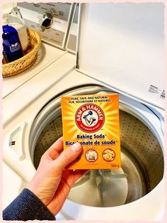 someone holding up a box of baking soda in front of a washing machine