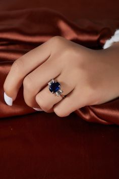 a woman's hand with a ring on it and a red satin material behind her