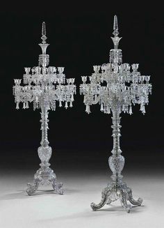 two crystal candelabras with candlesticks on stands, one in the shape of a cross