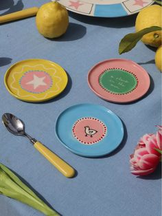 three plates and two spoons on a blue tablecloth with lemons, tulips and flowers