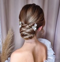 a woman with her hair in a low bun and flowers on the back of her head