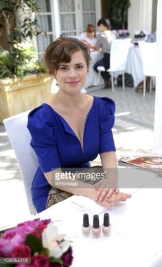 a woman sitting at a table with three nail polishes on her feet, smiling