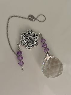 a silver necklace with amethyst beads hanging from it's side on a white surface