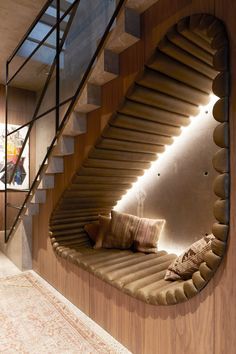 a curved staircase in the middle of a living room next to a couch with pillows on it