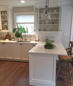 a kitchen with white cabinets and an island in the middle, surrounded by wood flooring