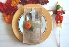 a place setting on a table with fall leaves