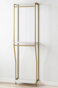 a white and gold shelving unit against a wall