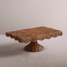 a wicker cake plate with scalloped edges sits on a tableclothed surface