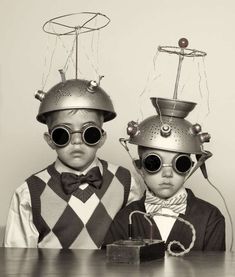 two young boys wearing metal helmets and glasses with wires attached to them, standing next to each other