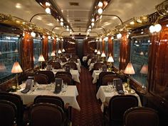 a dining car on a train with many tables and chairs set up for dinner,