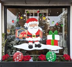 a window display with christmas decorations and santa clause on it's front windowsill