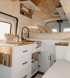 the interior of a camper with white cabinets and wood flooring on the walls