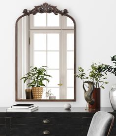 a mirror sitting on top of a dresser next to a chair and potted plant