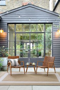 two chairs sitting on top of a rug in front of a building with large windows