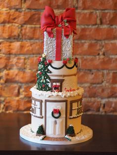 a three tiered cake decorated with christmas decorations and bows on top of a table