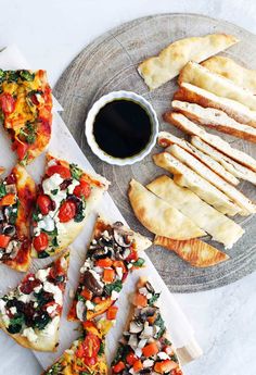 several slices of pizza with different toppings on a plate next to some dipping sauce