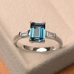 This ring features a 6*8 mm emerald cut London blue topaz and sterling silver finished with rhodium. Customization is available. It is made by hand, and it will take about 7 days to finish the ring after your payment is completed. Main stone: London blue topaz Main stone weight: Approx 2.01 ct Metal type: sterling silver finished with rhodium Accent stone: CZ Customization is available, I also can make it with 14k solid gold (white or yellow or rose) and diamond accent stone, just feel free to c Silver Halo Ring, Ring Emerald Cut, Blue Topaz Engagement Ring, Blue Gemstone Rings, Ring Gifts, Topaz Engagement Ring, London Blue Topaz Ring, Silver Anniversary, Emerald Engagement Ring Cut