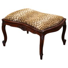 a leopard print foot stool with wooden legs