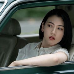 a woman sitting in the driver's seat of a green car