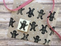 a brown paper bag with black and white gingerbreads on it next to a red ribbon