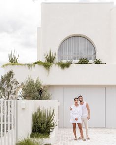 two people standing in front of a white building