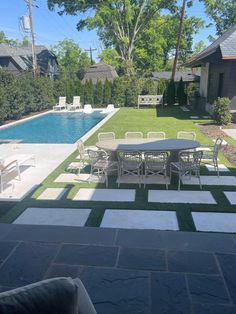 an outdoor patio with tables and chairs next to a swimming pool in the back yard