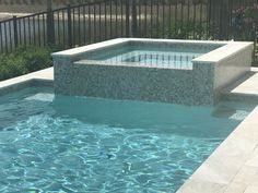 an empty swimming pool with steps leading up to the bottom and above it, in front of a fenced area