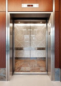 an elevator with glass doors and marble flooring