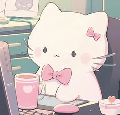 a white kitty sitting at a desk with a pink coffee mug and laptop on it