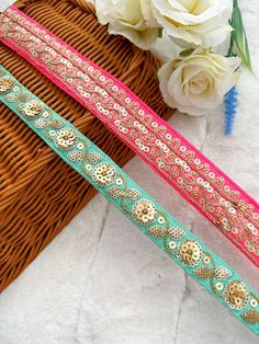 two different colored ribbons sitting on top of a basket next to white roses and flowers