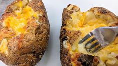 two baked potatoes with cheese and a fork