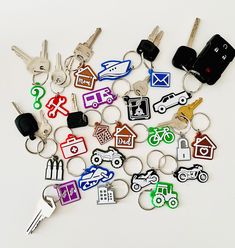 many different keychains and car keys on a white surface with various symbols in the shape of cars