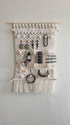 a white wall hanging with lots of different items attached to it's sides and fringes