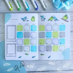 an open planner with birds on it next to markers, pens and paper clippings