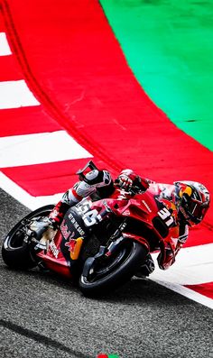 a man riding a motorcycle on top of a race track next to a green and red flag