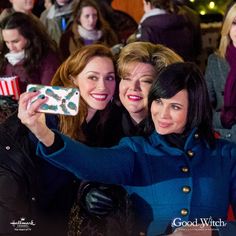 three women taking a selfie in front of an audience at a christmas event with their cell phone