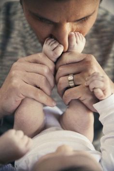 a man holding a baby in his hands and touching it's thumb with both hands