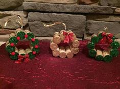 three wine cork christmas decorations on a red tablecloth next to a brick wall and stone fireplace