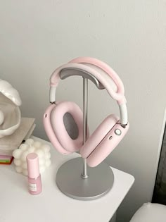 a pair of pink headphones sitting on top of a table next to a white vase