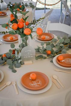 the table is set with orange plates and silverware