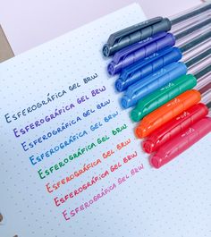 five different colored pens sitting on top of a notebook