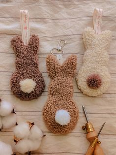 three stuffed animals sitting on top of a bed next to scissors and cotton floss