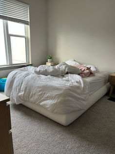 an unmade bed sitting in a bedroom next to a window