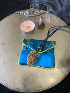 a small blue bag sitting on top of a table next to a candle and some bottles